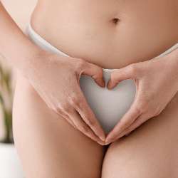 Young woman in panties making heart shape with hands at home